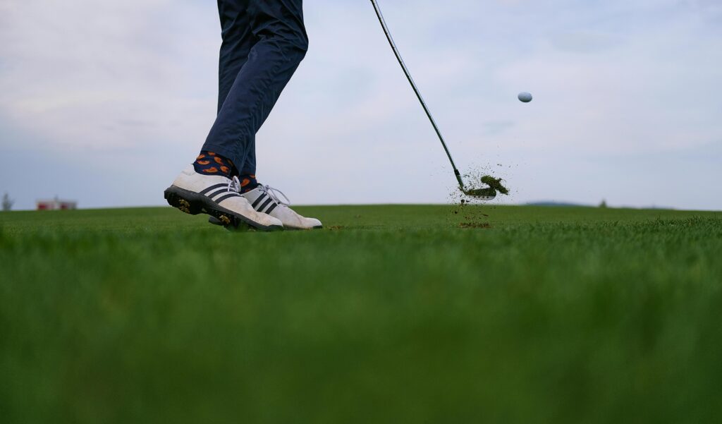 Golfer mid-swing during a pain-free round after receiving Titleist-certified physical therapy and robotic muscle treatment in Lake Orion.